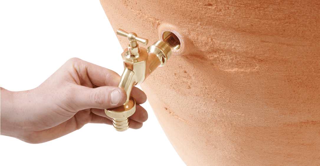 une main tient un robinet sur la cuve aérienne Antik Amphore terracotta de Sotra'O